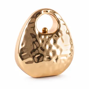 Fashionable hammered gold metal handbag with oval shape and unique round handle for evening events