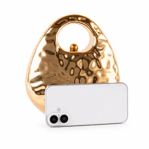 Mini gold metallic evening bag shown with a smartphone to display its compact size