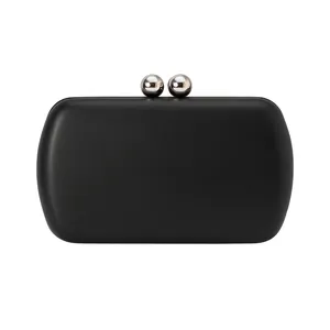 Détail d'une pochette de soirée noire minimaliste avec un fermoir boule en métal argenté