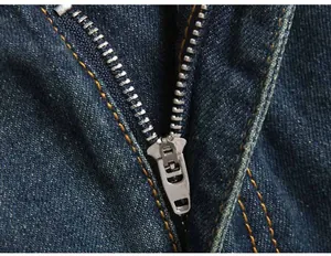 Detailed close-up of premium metal zipper and orange stitching on deep blue denim jeans