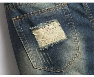 Detail of distressed back pocket on men's jeans with vintage wash and repair patches