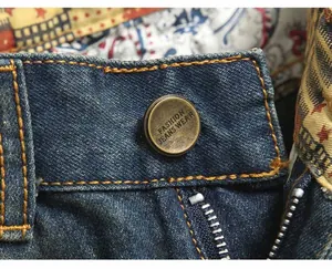Macro view of vintage bronze button and metal zipper on blue distressed denim jeans