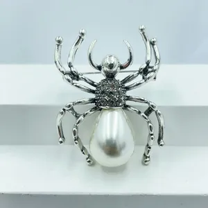 Close-up of vintage silver spider brooch featuring a large teardrop pearl and grey rhinestones