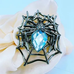 Macro shot of spider brooch with blue pear-cut gemstone and dark crystal details
