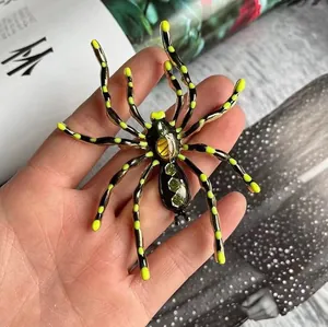 Detailed close-up of a spider brooch with yellow dots and green gemstone inlay details
