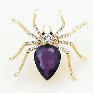 Detailed macro view of a gold spider brooch with purple teardrop gem and rhinestones