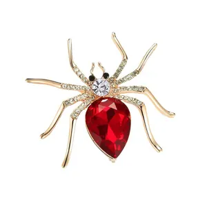 Spider brooch with golden metal legs, white crystals and large pear-cut red stone