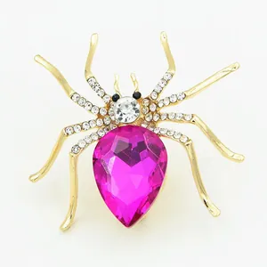 Detailed close-up of a golden spider brooch featuring pink teardrop gemstone and crystals