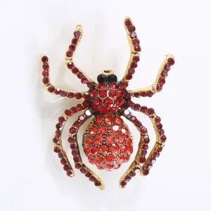 Macro detail of a crystal-encrusted spider brooch with red rhinestones on gold finish