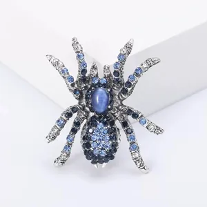 Macro shot of spider brooch with blue rhinestones and cat eye stone on white stand