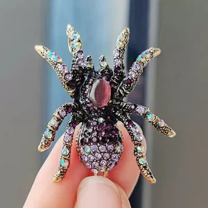 Macro shot of a purple crystal spider brooch with a cat eye gemstone held by hand