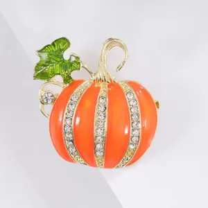 Macro shot of orange enamel pumpkin brooch with white crystals on a gold base