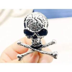 Gothic silver skull and crossbones brooch with detailed metallic texture held in hand