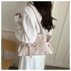 Chic light pink underarm bag with buckle detail shown on a model in a minimalist setting