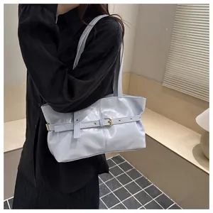 Close-up of light blue glossy leather underarm bag with decorative belt and metallic eyelets