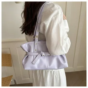 Detail view of lavender purple leather shoulder bag with decorative straps and metal eyelets