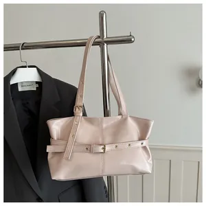 Detail of adjustable metal eyelet straps and matte PU texture on a cream tote bag