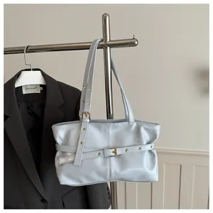 Detail of light blue pleated shoulder bag with gold metal buckle and grommet accents