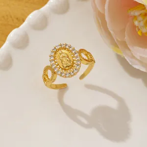 Detail of gold-plated Virgin Mary ring with zirconia stones on a white ceramic plate