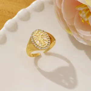 Detail of gold oval ring with Virgin Mary relief and cubic zirconia halo on white plate