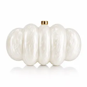 Dettaglio della pochette in acrilico bianco con chiusura dorata e trama perlata