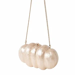 Dettaglio della borsa da sera in acrilico bianco perlato con catena d'oro e design a onde