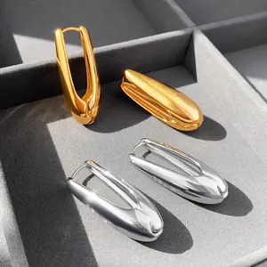 Detailed macro view of minimalist gold and silver teardrop earrings on gray velvet