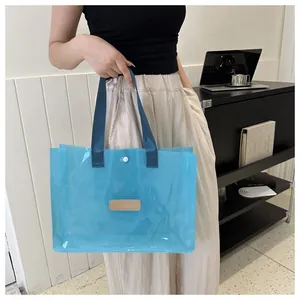 Close-up of blue transparent PVC tote bag with magnetic clasp and dark fabric handles