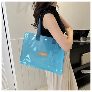 Detail view of ice blue transparent tote bag with dark blue handles and snap closure