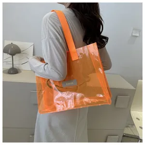Detail of orange transparent PVC tote bag with stylish woven strap and logo patch