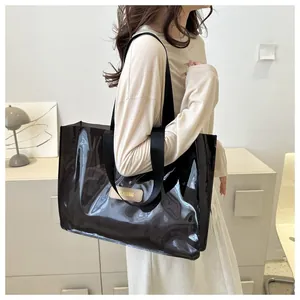 Detail of semi-transparent black PVC tote bag featuring leather label and nylon straps