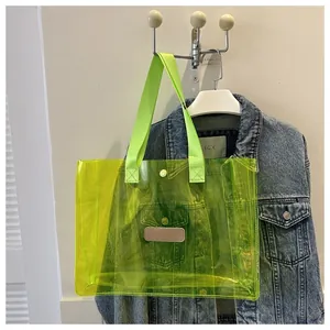 Close-up of fluorescent green transparent PVC tote bag with pink patch and woven handle