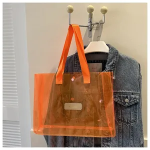 Detail of transparent orange PVC tote bag with leather logo patch on blue denim jacket