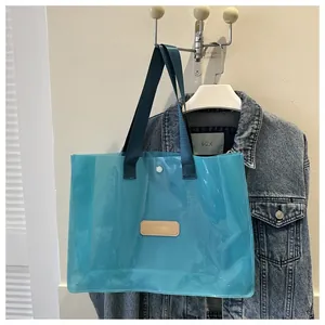 Detail of blue transparent PVC tote bag with navy fabric handles and magnetic closure