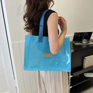 Chic blue transparent tote bag with dark navy straps and logo patch shown on a model