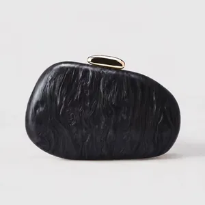 Detailed view of irregular acrylic clutch bag with gray marble texture and gold clasp