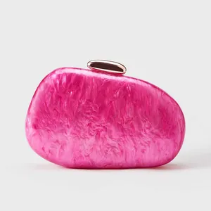 Macro view of rose pink marble acrylic clutch bag with polished gold metal clasp