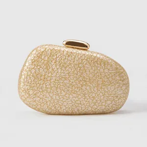 Close-up of champagne gold pebble clutch bag with polished clasp and textured finish