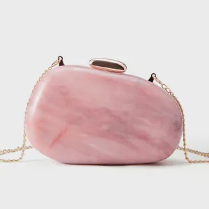 Detail of pink marble acrylic clutch featuring rose gold clasp and sleek metal chain