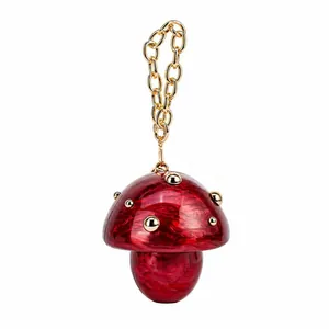 Macro detail of red marble acrylic mushroom bag with gold rivets and thick chain
