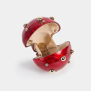 Detail of red marble acrylic mushroom clutch with gold rivets and chain strap