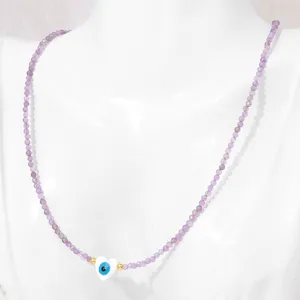 Detail of 2mm purple crystal beaded necklace with evil eye heart shell charm on neck