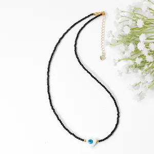 Macro detail of 2mm black beaded necklace with heart-shaped evil eye pendant and gold clasp
