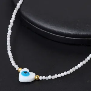 Macro shot of 2mm faceted white beads and heart-shaped blue evil eye pendant on necklace