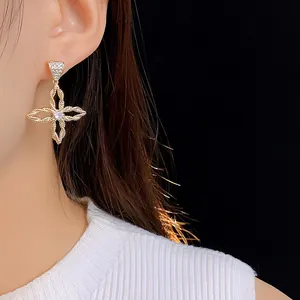 Details von blumenförmigen Gold-Ohrringen mit Zirkonia und geflochtener Textur am Ohr