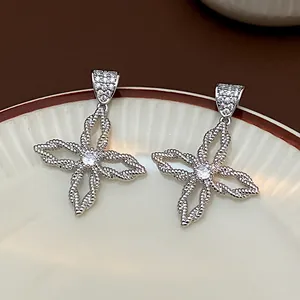 Makroaufnahme der silbernen Blumenohrringe mit Zirkon-Inlays und hohlen Blütenblättern