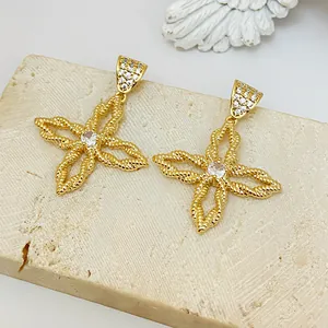 Detail von goldene Ohrringe in Blumenform mit Zirkonia und gedrehte Textur