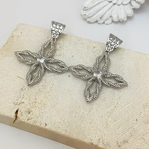 Makroaufnahme von silbernen Blumenohrringen mit Kordelstruktur und Zirkon-Inlay
