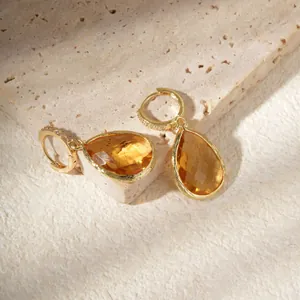 Elegant gold drop earrings with pear-cut amber gemstones on a minimalist stone base