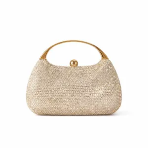 Macro shot of luxury gold rhinestone clutch bag with curved metal handle and crystal finish